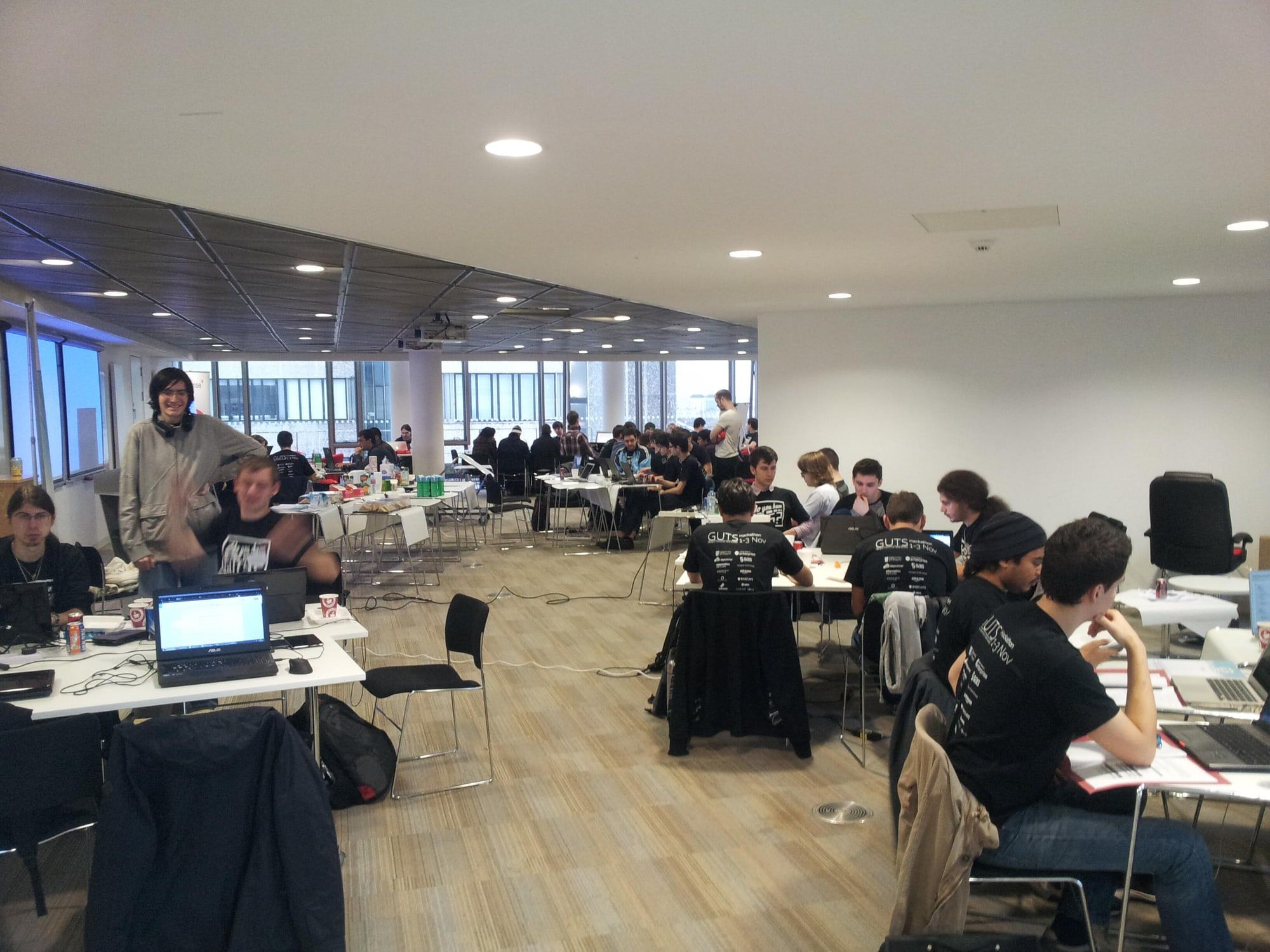 A long, bright room with hackers at laptops on rows of tables, the first GUTS hackathon under way.