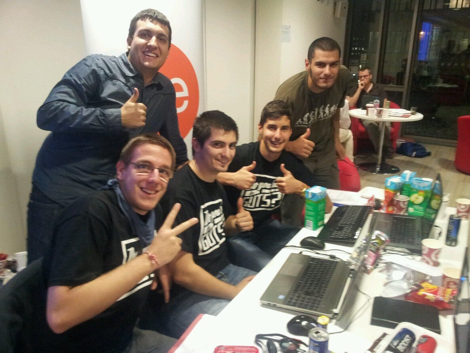 Team Javatar in black GUTS T-shirts posing at their laptops, giving thumbs up.