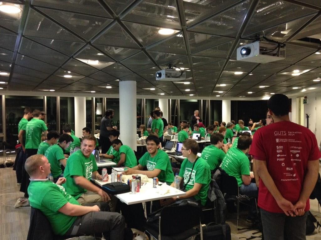 A large hall of hackers in green T-shirts seated at tables before kick-off.