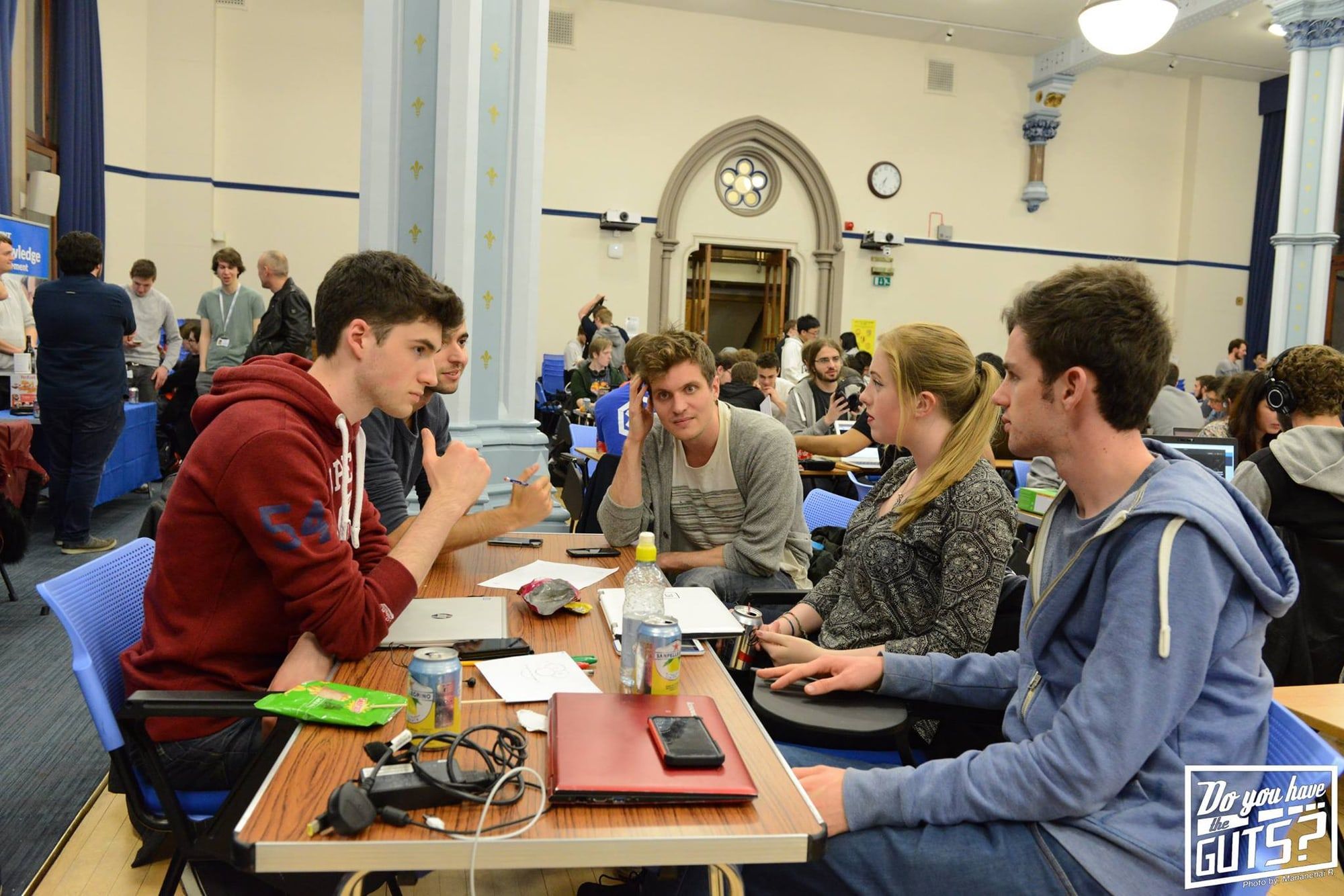 A team working around a table in the Hunter Halls, more teams behind them.